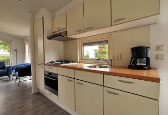 Moderne kabinekøkken i Chalet Basic på De Woudhoeve, Holland, med komfur, ovn og kaffemaskine.