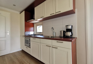 Kitchenette moderne au Chalet Basic de De Woudhoeve, Pays-Bas, avec évier, plaques et cafetière.