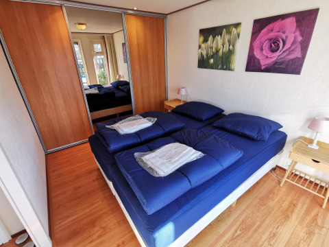 Dormitorio acogedor en Chalet Basic en De Woudhoeve, Países Bajos, con ropa de cama azul y armario con espejo.