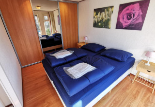 Dormitorio acogedor en Chalet Basic en De Woudhoeve, Países Bajos, con ropa de cama azul y armario con espejo.