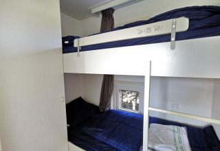Lits superposés avec draps bleu foncé dans une chambre du Chalet Basic à De Woudhoeve, Pays-Bas.