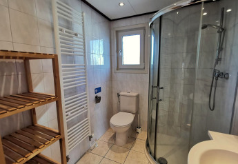 Moderne badeværelse i Chalet Basic ved De Woudhoeve, Nederlandene, med brusekabine og træhylder.