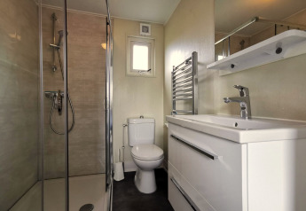 Moderne badeværelse i Chalet Basic ved De Woudhoeve, Nederlandene, med bruser, toilet og vask.