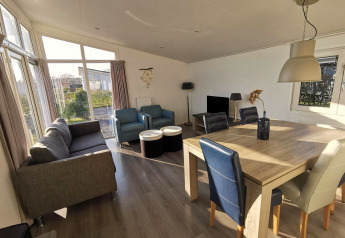 Lys og rummelig stue i Chalet Basic på De Woudhoeve i Holland med store vinduer og moderne møbler.