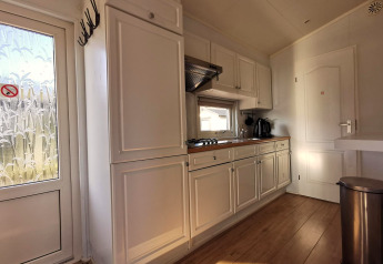 Lyst køkken i Chalet Basic på De Woudhoeve, Holland, med hvide skabe og trægulv.