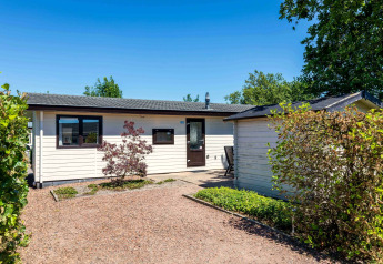 Chalet Basic ved De Woudhoeve i Holland, vist på en solrig dag med haver og grønne omgivelser.