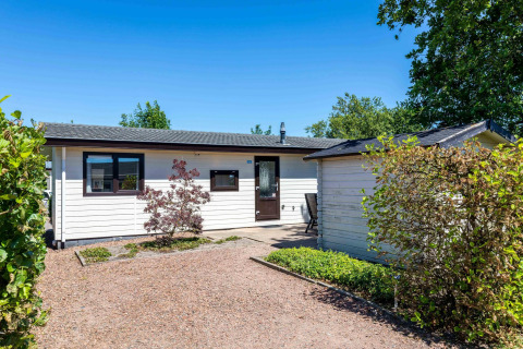 Chalet Basic à De Woudhoeve, aux Pays-Bas, photographié par une journée ensoleillée avec jardin et verdure.