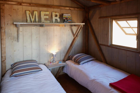 Gemütliche Holzhütte mit zwei Einzelbetten im Cabane Lodge Comfort bei Flower Camping Les Ondines, Frankreich.