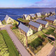 Luftfoto af strandhytter ved Villa Oesterdam i Oesterdam Resort, Holland, med udsigt over vand og grønne omgivelser.