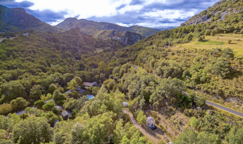 Vista aerea del campeggio «des Randonneurs» in Occitania, Francia, circondato da colline e foreste verdi.