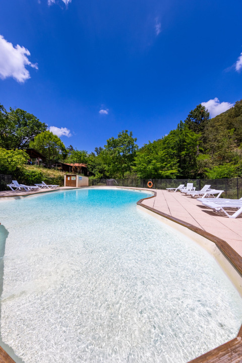 Piscina al Campeggio des Randonneurs in Occitania, Francia, circondata dal verde e da lettini prendisole.
