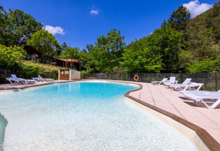 Piscina al Campeggio des Randonneurs in Occitania, Francia, circondata dal verde e da lettini prendisole.