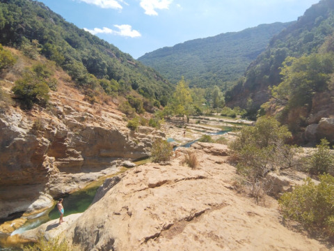 Valle rocciosa con fiume e colline verdi presso il Campeggio des Randonneurs in Occitania, Francia.