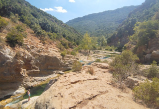 Valle rocciosa con fiume e colline verdi presso il Campeggio des Randonneurs in Occitania, Francia.
