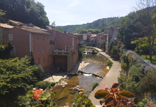 Vista di un pittoresco villaggio e fiume al Campeggio 'des Randonneurs' in Occitania, Francia, immerso nel verde.