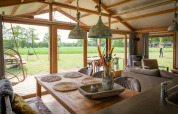 Intérieur d’un lodge de luxe avec table à manger face à la prairie à Landrijk de Reesprong, Pays-Bas.