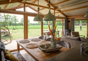 Interior de cabaña de lujo con mesa de comedor y vista al campo verde en Landrijk de Reesprong, Países Bajos.