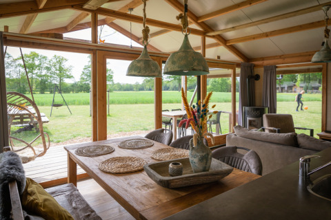 Interno di un lodge di lusso con tavolo da pranzo e vista sui campi verdi a Landrijk de Reesprong, Paesi Bassi.