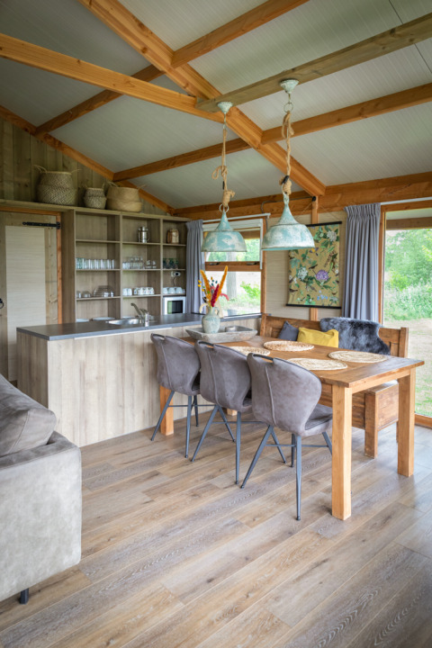 Innenraum einer Luxuslodge mit Holzdecke, Essbereich und Küche im Landrijk de Reesprong in den Niederlanden.