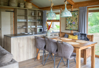 Innenraum einer Luxuslodge mit Holzdecke, Essbereich und Küche im Landrijk de Reesprong in den Niederlanden.