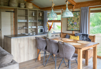 Innenraum einer Luxuslodge mit Holzdecke, Essbereich und Küche im Landrijk de Reesprong in den Niederlanden.