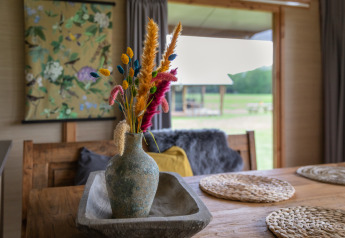 Gemütlicher Speiseraum in einer Lodge mit Vase und Trockenblumen bei Landrijk de Reesprong, Niederlande.