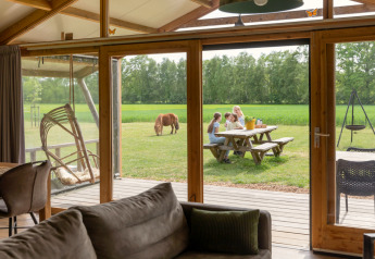 Vista desde el interior de una lodge de lujo en Landrijk de Reesprong, Países Bajos, con familia y pony fuera.