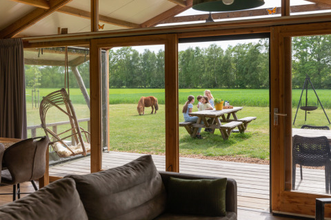 Vista dall'interno di un lodge di lusso a Landrijk de Reesprong nei Paesi Bassi con famiglia all'esterno.