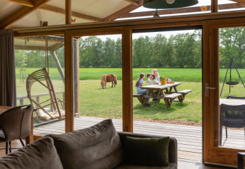 Blick aus einer Luxuslodge bei Landrijk de Reesprong, Niederlande, auf Familie am Picknicktisch im Grünen.