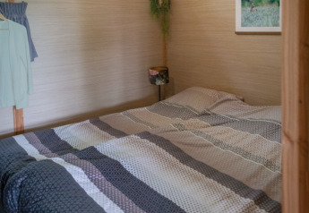 Photo intérieure d’un lodge douillet avec lit double, poutres en bois et puits de lumière à Landrijk de Reesprong.