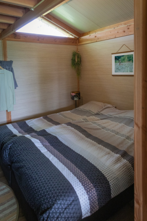 Foto interna di un lodge accogliente con letto matrimoniale e travi in legno a Landrijk de Reesprong nei Paesi Bassi.