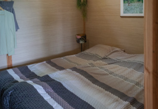 Foto interna di un lodge accogliente con letto matrimoniale e travi in legno a Landrijk de Reesprong nei Paesi Bassi.