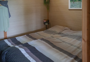 Innenaufnahme einer gemütlichen Lodge mit Doppelbett, Holzbalken und Oberlicht in Landrijk de Reesprong.