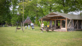 Une famille profite de l'extérieur d'un lodge Luxe moderne avec terrasse au cœur de la verdure.