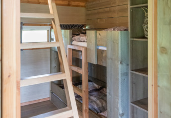 Innenraum der Luxe Lodge im Landrijk de Reesprong, Niederlande, mit Holzleiter, Etagenbetten und Oberlicht.