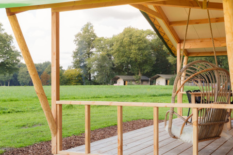 Uitzicht vanaf houten terras bij Luxe lodge incl oven op Landrijk de Reesprong, Nederland, met velden en tenten.