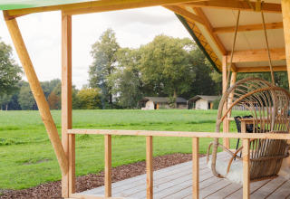 Uitzicht vanaf houten terras bij Luxe lodge incl oven op Landrijk de Reesprong, Nederland, met velden en tenten.