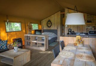 Binnenzicht van een luxe safaritent bij Landrijk de Reesprong in Nederland met houten meubelen.