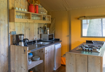 Rustic kitchen inside a luxury safari tent at Landrijk de Reesprong in the Netherlands, featuring wooden decor.