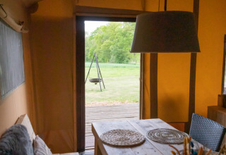 Binnenzicht van een luxe safaritent bij Landrijk de Reesprong, Nederland, eettafel met placemats.