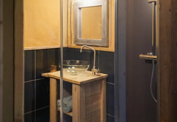 Salle de bain d'une tente safari de luxe à Landrijk de Reesprong, Pays-Bas, avec vasque en verre.