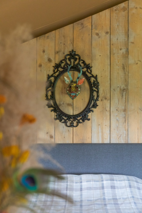 Interior of a luxury safari tent at Landrijk de Reesprong, Netherlands, featuring decorative wall art and wood.