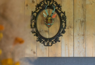 Interior of a luxury safari tent at Landrijk de Reesprong, Netherlands, featuring decorative wall art and wood.