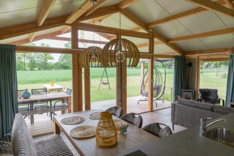 Interno di un lodge di lusso con grandi vetrate e vista su prato verde a Landrijk de Reesprong, Paesi Bassi.