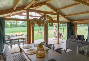 Intérieur d’un lodge moderne avec grandes fenêtres et vue sur la nature chez Landrijk de Reesprong aux Pays-Bas.