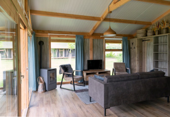 Modern living area inside a Luxe lodge at Landrijk de Reesprong, Netherlands, with large windows and cozy decor.