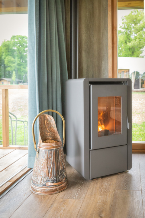 Stufa a legna moderna e secchio in ceramica vicino a una finestra in un lodge Luxe a Landrijk de Reesprong, Paesi Bassi.