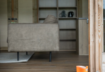 Oranje regenlaarzen bij de ingang van een luxe lodge op Landrijk de Reesprong, Nederland, met houten interieur.