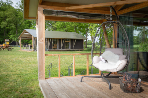 Zona relax con poltrona sospesa sulla veranda della Luxe lodge a Landrijk de Reesprong, Paesi Bassi.