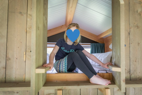 Bambina che gioca in un rifugio di legno nella Luxe lodge a Landrijk de Reesprong, Paesi Bassi, ambiente accogliente.